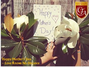 Hand holding a white flower beside a Mother's Day note.