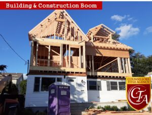 Two houses under construction with wooden frames against a blue sky.