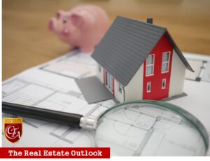 A model house, piggy bank, and blueprints symbolizing real estate investment.