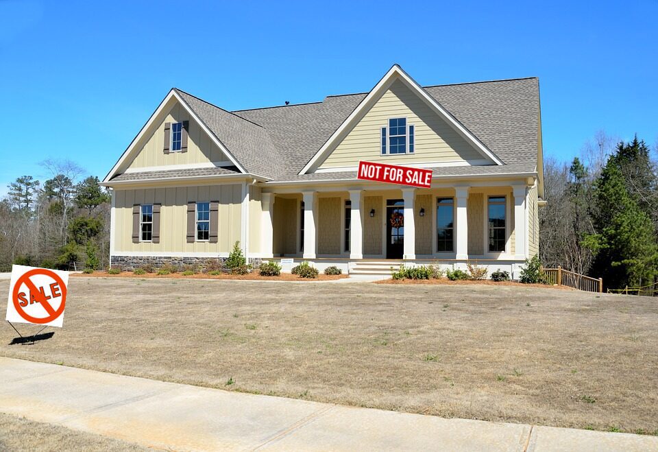 A beige house with a 'Not For Sale' sign on the porch.