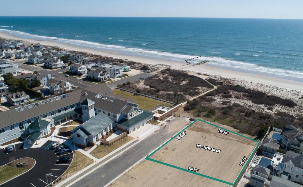 Aerial view of a coastal neighborhood with vacant lots near the beach.