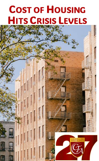 Brick apartment building with fire escapes and leafy tree branches.