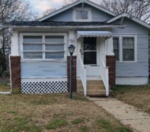 Small gray house with a white porch and steps.
