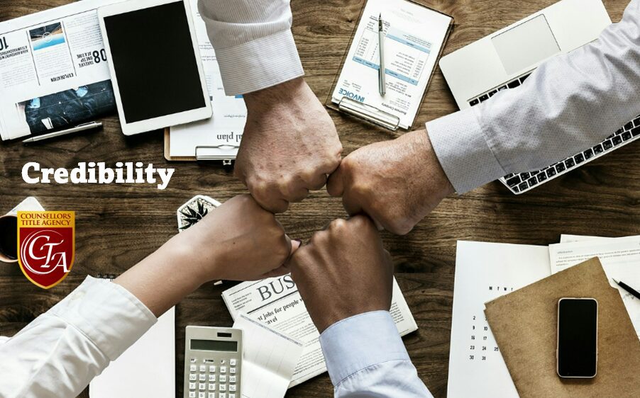 Four diverse hands joining in a fist bump over business documents and devices.