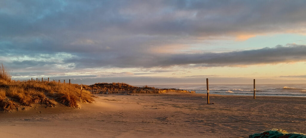 Sandy beach under a cloudy sunset sky.