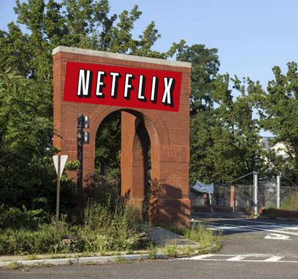 Brick archway with Netflix sign, overgrown plants.