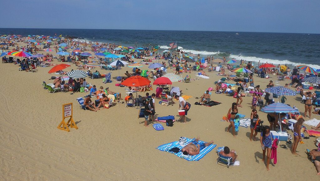 Crowded beach with colorful umbrellas and sunbathers.