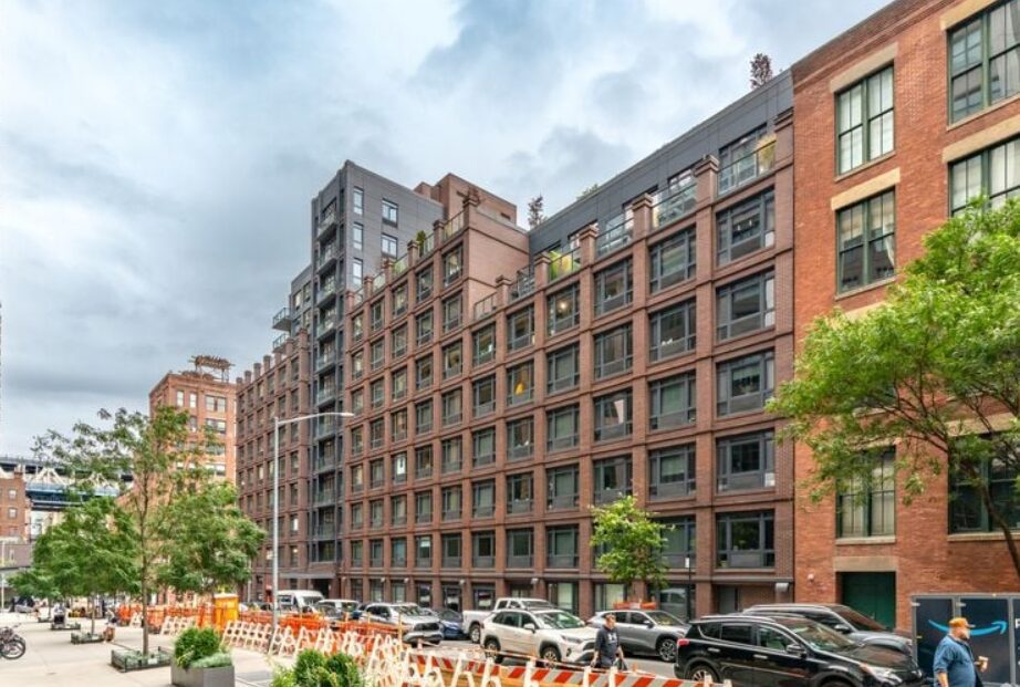 Modern brick and glass apartment buildings on a city street with parked cars.